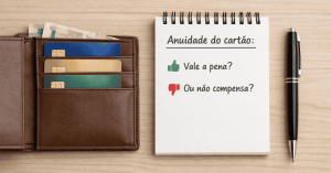 Carteira com vários cartões de crédito e cédulas de dinheiro ao lado de um bloco de notas com anotações sobre anuidade do cartão de crédito, representando análise de custos e benefícios do uso do cartão de crédito.
